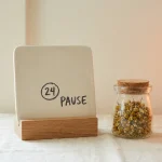 Calendrier marquant une pause à côté d'un bocal d'herbe séchée, sur fond clair