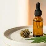 Produits CBD sur fond clair : flacon d'huile, fleur et feuille de chanvre